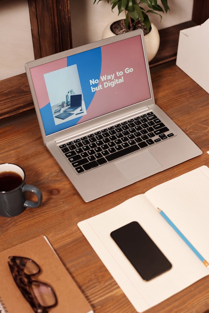 A neatly organized desk featuring a laptop displaying digital content, coffee, and office supplies.